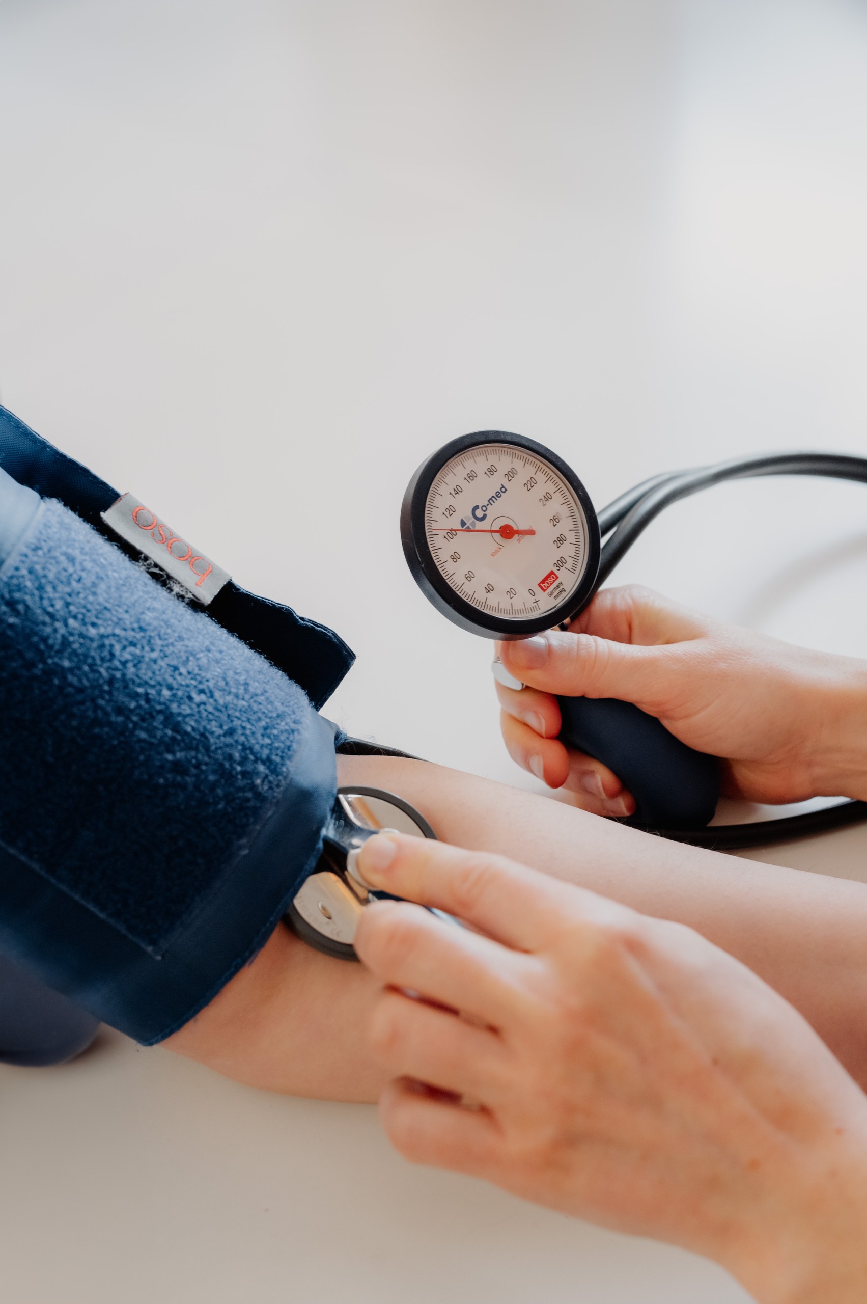Die Arzthelferin steht vor einer Patientin, die auf einem Stuhl sitzt. Die Arzthelferin führt eine Behandlung bei der Patientin durch.